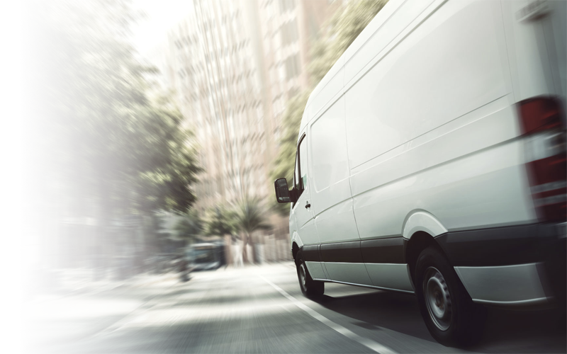 White delivery van travelling along a city street