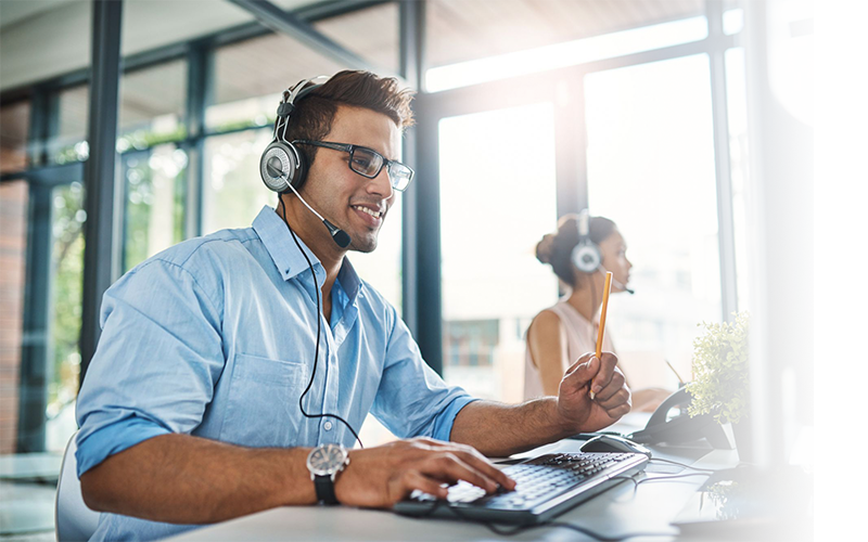 Customer service representative wearing a headset and working at a computer