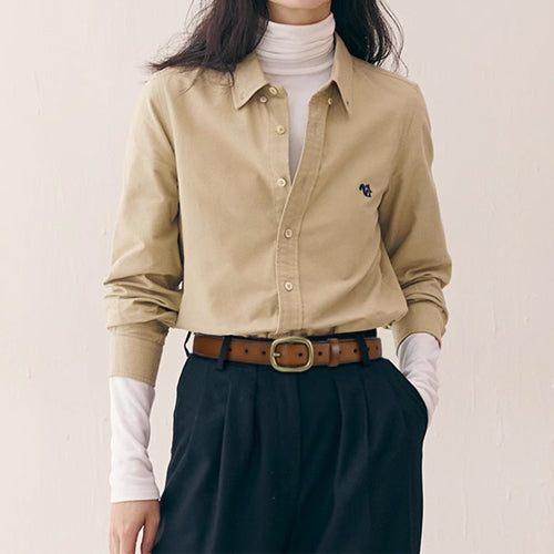 Tan belt styled with a beige shirt and dark high-waisted trousers